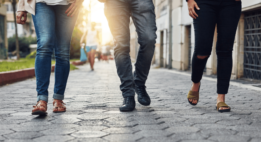 photo of three pairs of legs walking down the street