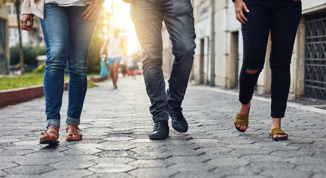photo of three pairs of legs walking down the street